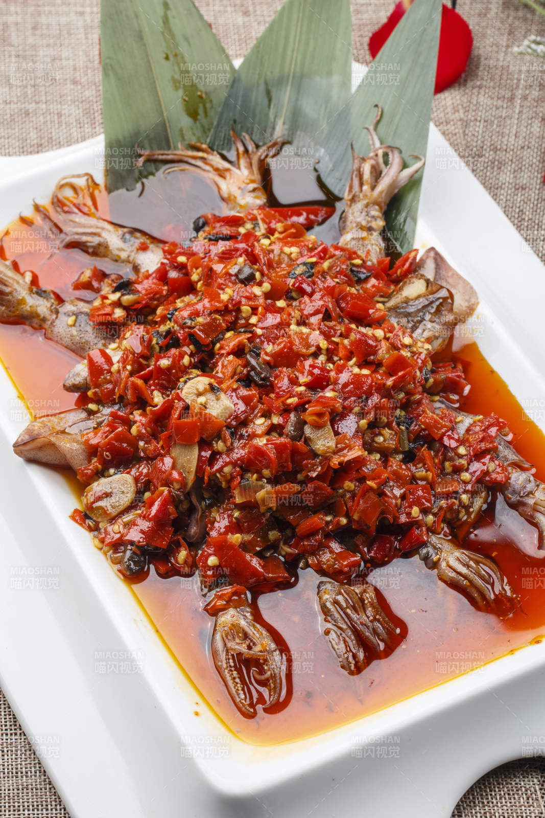 白色长方形瓷盘装的豆瓣酱香辣红油炒海鲜小管