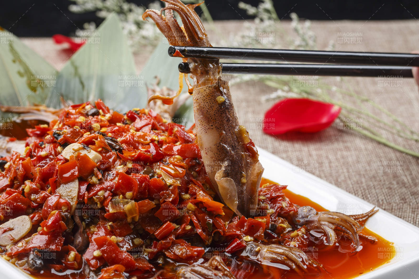 白色长方形瓷盘装的豆瓣酱香辣红油炒海鲜小管