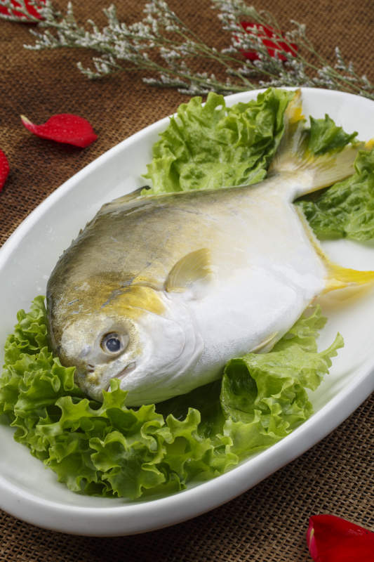 白色椭圆瓷盘装的新鲜金昌鱼