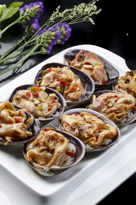 鼎形瓷盘装的海鲜炭烤紫石房蛤天鹅蛋