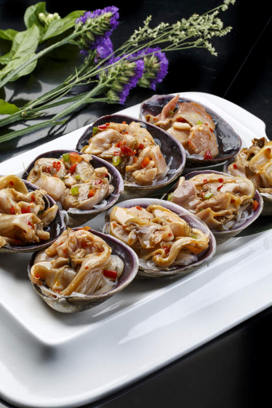 鼎形瓷盘装的海鲜炭烤紫石房蛤天鹅蛋