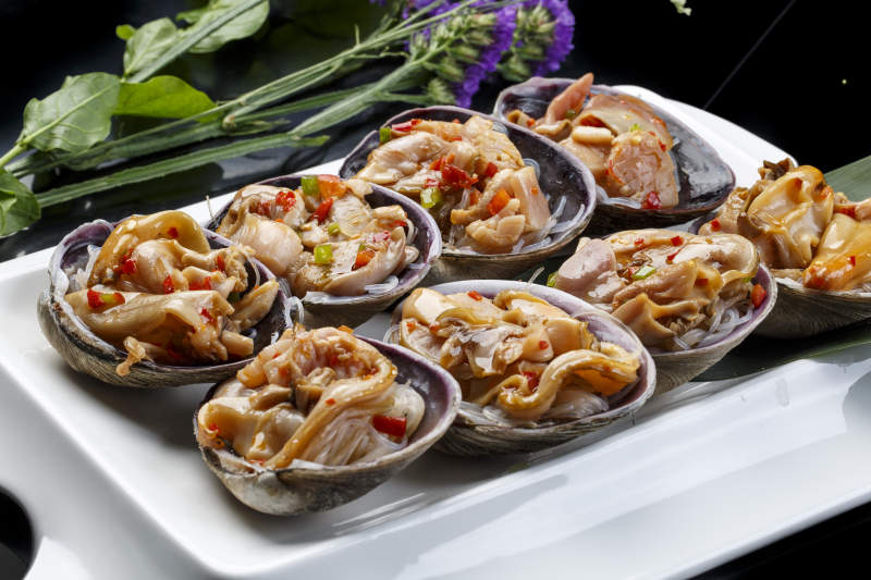 鼎形瓷盘装的海鲜炭烤紫石房蛤天鹅蛋