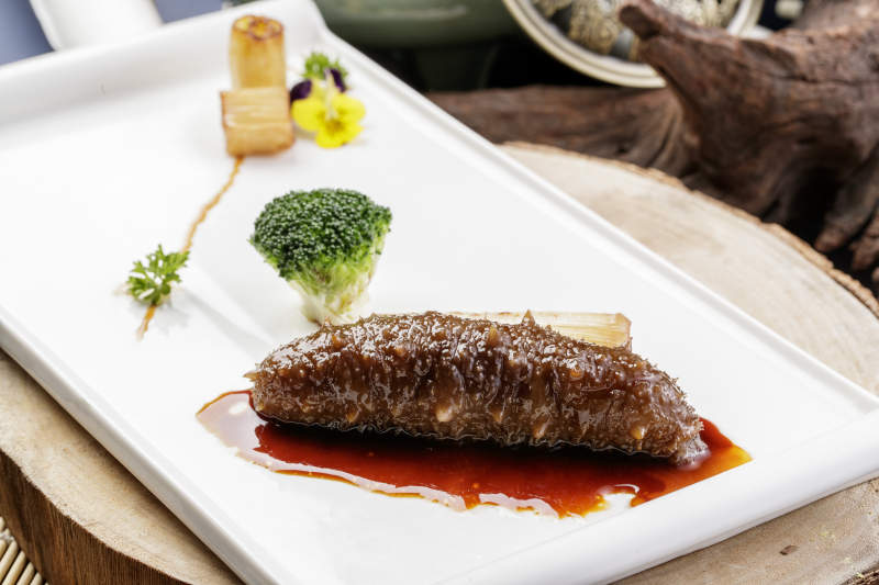 白色瓷盘装的捞汁梅花参