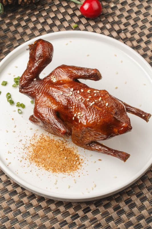 圆形白瓷盘装的港式脆皮乳鸽摆放在餐垫上