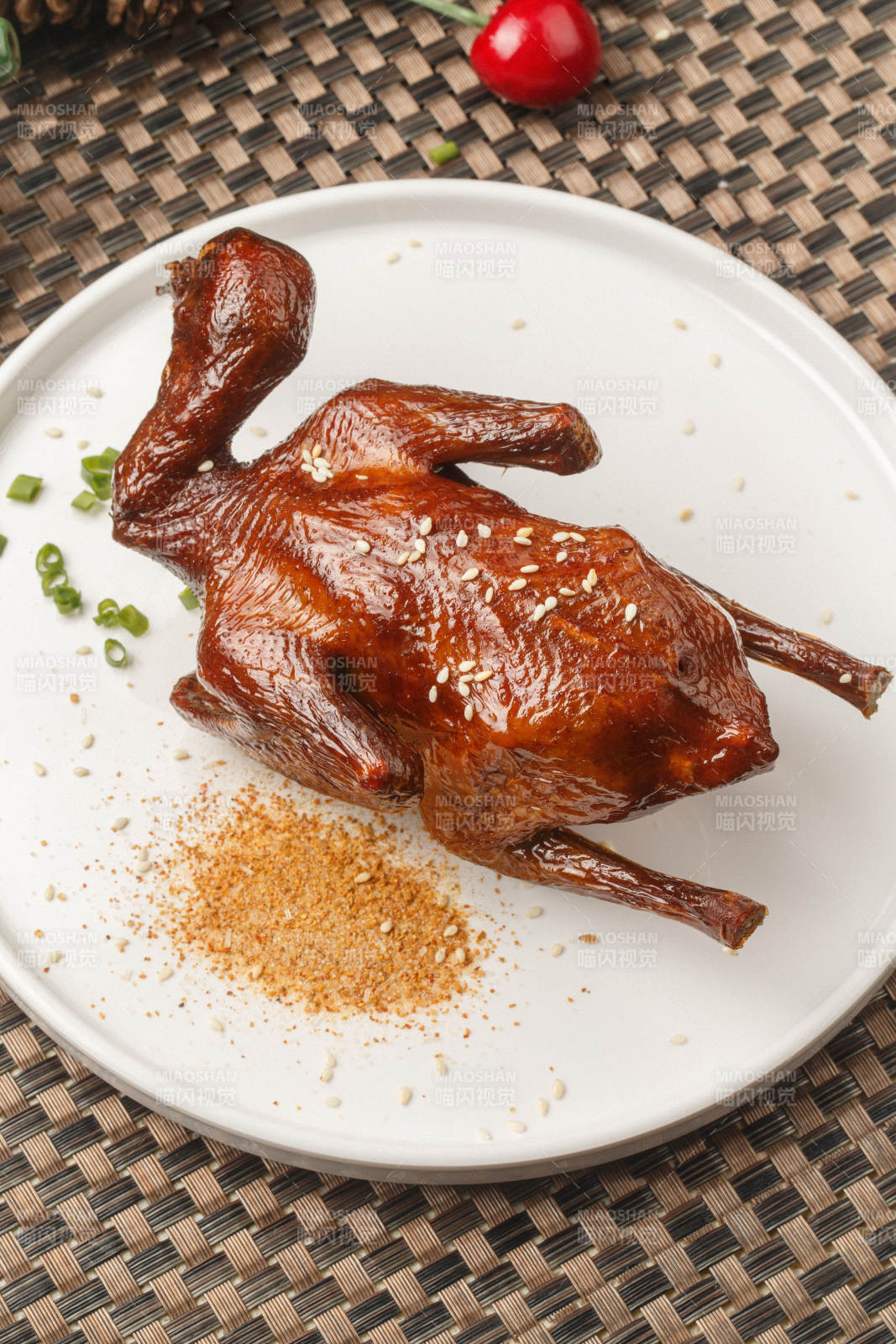 圆形白瓷盘装的港式脆皮乳鸽摆放在餐垫上