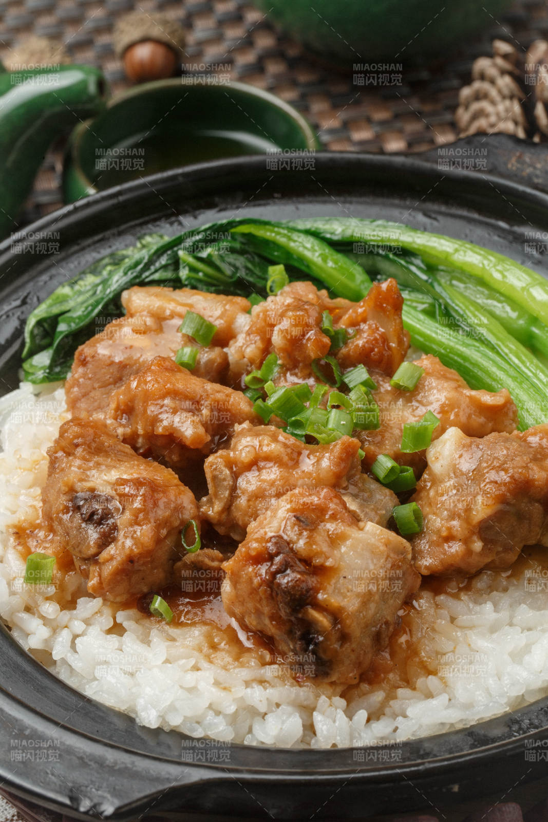 黑色砂锅装的排骨芥蓝煲仔饭摆放在餐布上