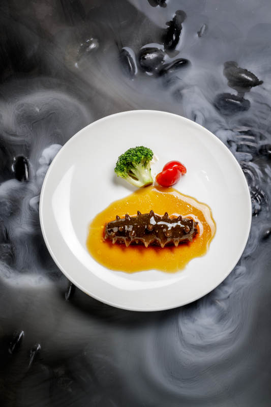 鲍汁扣辽参摆放在干冰缭绕的水中