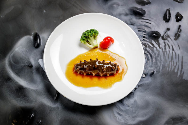 鲍汁扣辽参摆放在干冰缭绕的水中