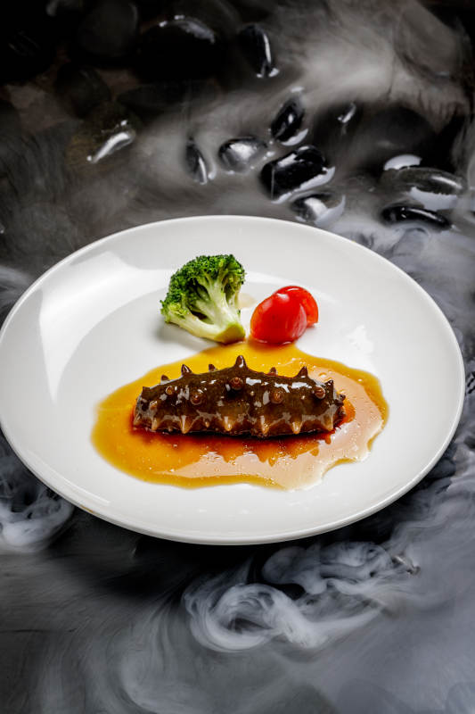 鲍汁扣辽参摆放在干冰缭绕的水中