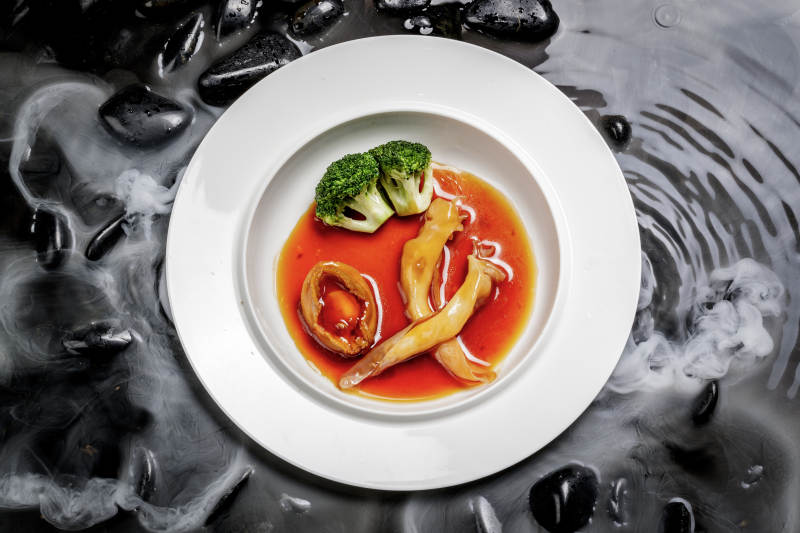 鲍汁鲍鱼烩花胶摆放在干冰缭绕的水中