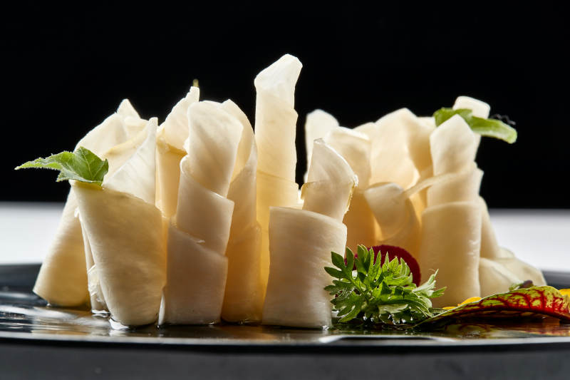 黑色瓷餐具装的鲜杏鲍菇刺身卷