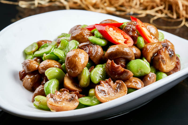 白色瓷盘装的塞外口蘑小炒青蚕豆