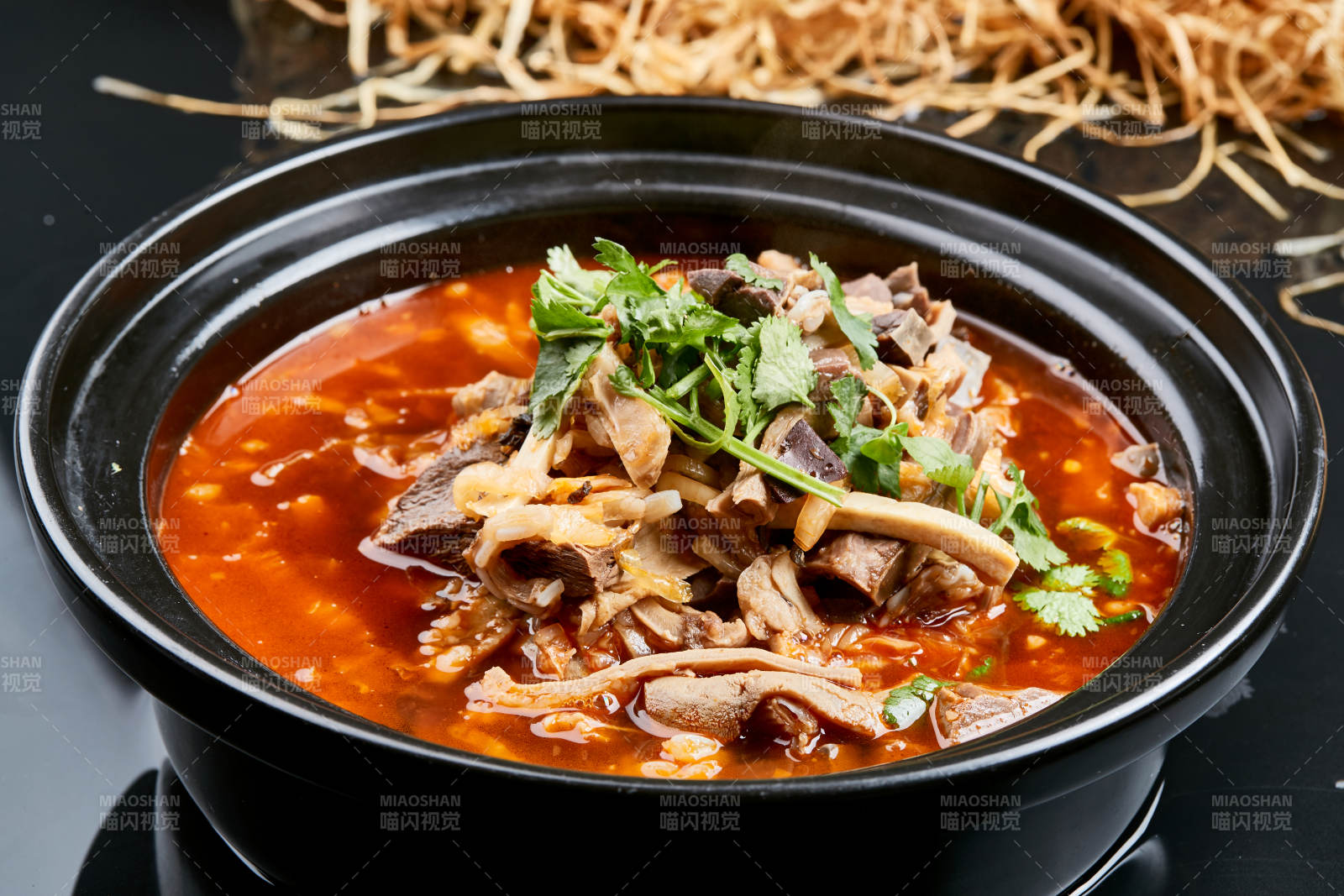 黑色背景上的砂锅香辣红油羊杂煲