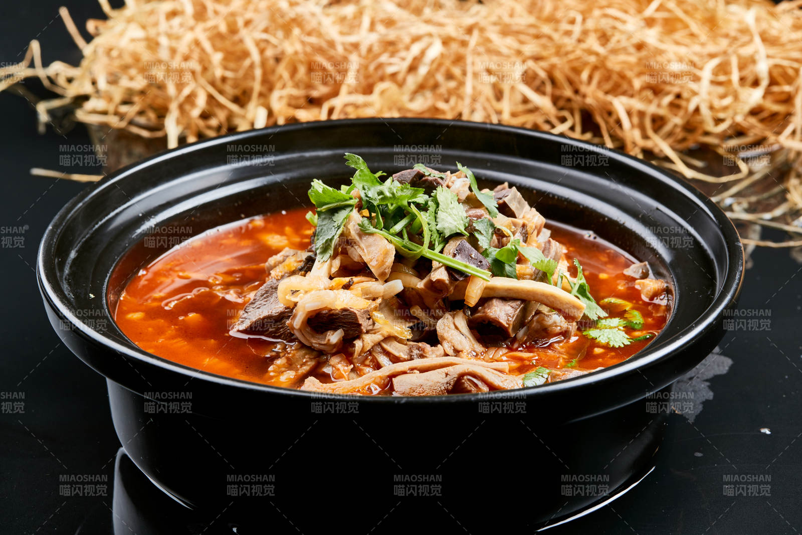 黑色背景上的砂锅香辣红油羊杂煲