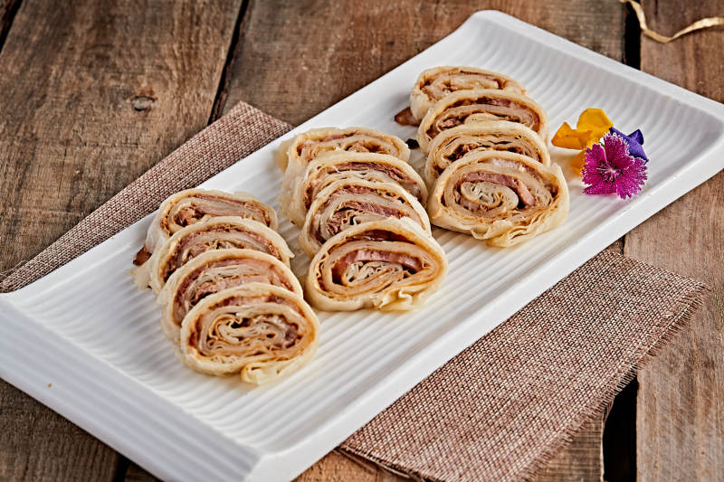 白色瓷盘装的大饼卷熏肉