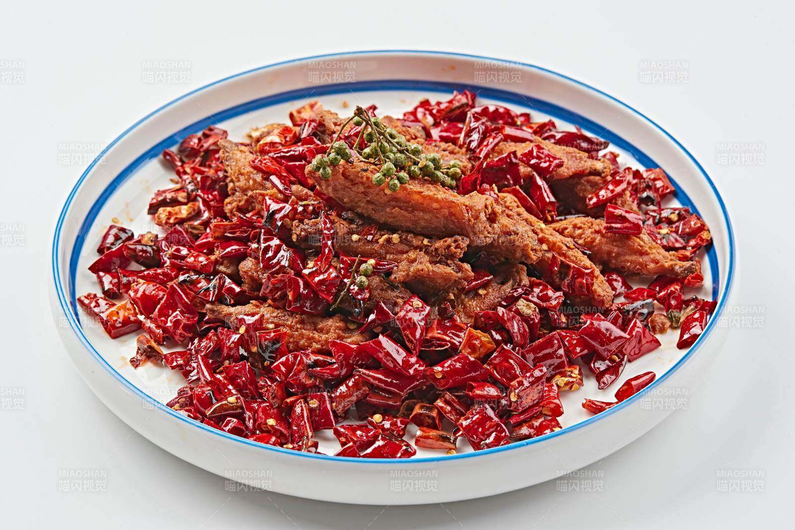 白色瓷盘装的川香油炸麻辣鸡翅中