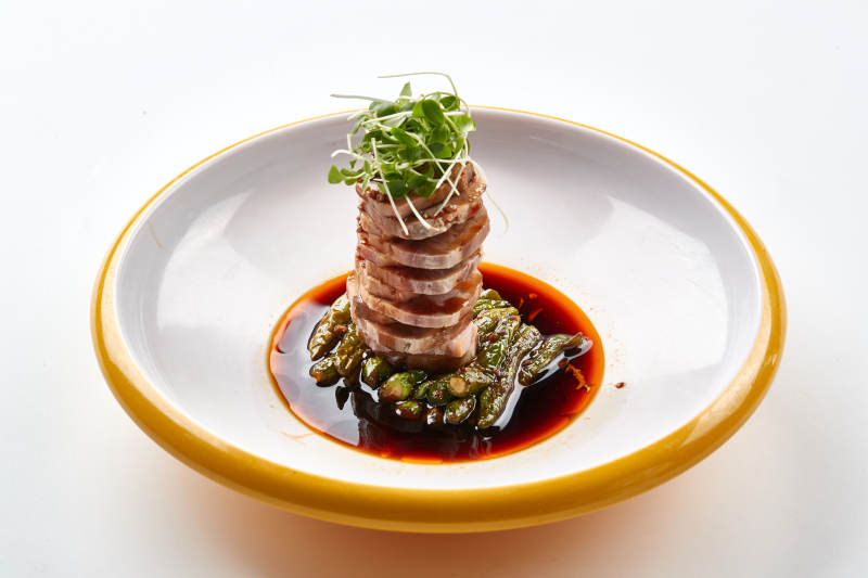 精美瓷盘装的压制熏肘花切片配香椿苗