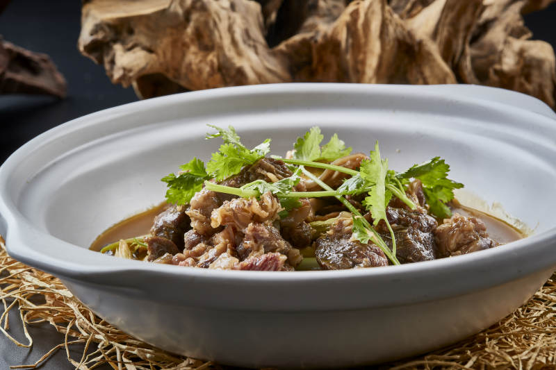 白色砂锅装的蒜苗浓汤炖牛腩