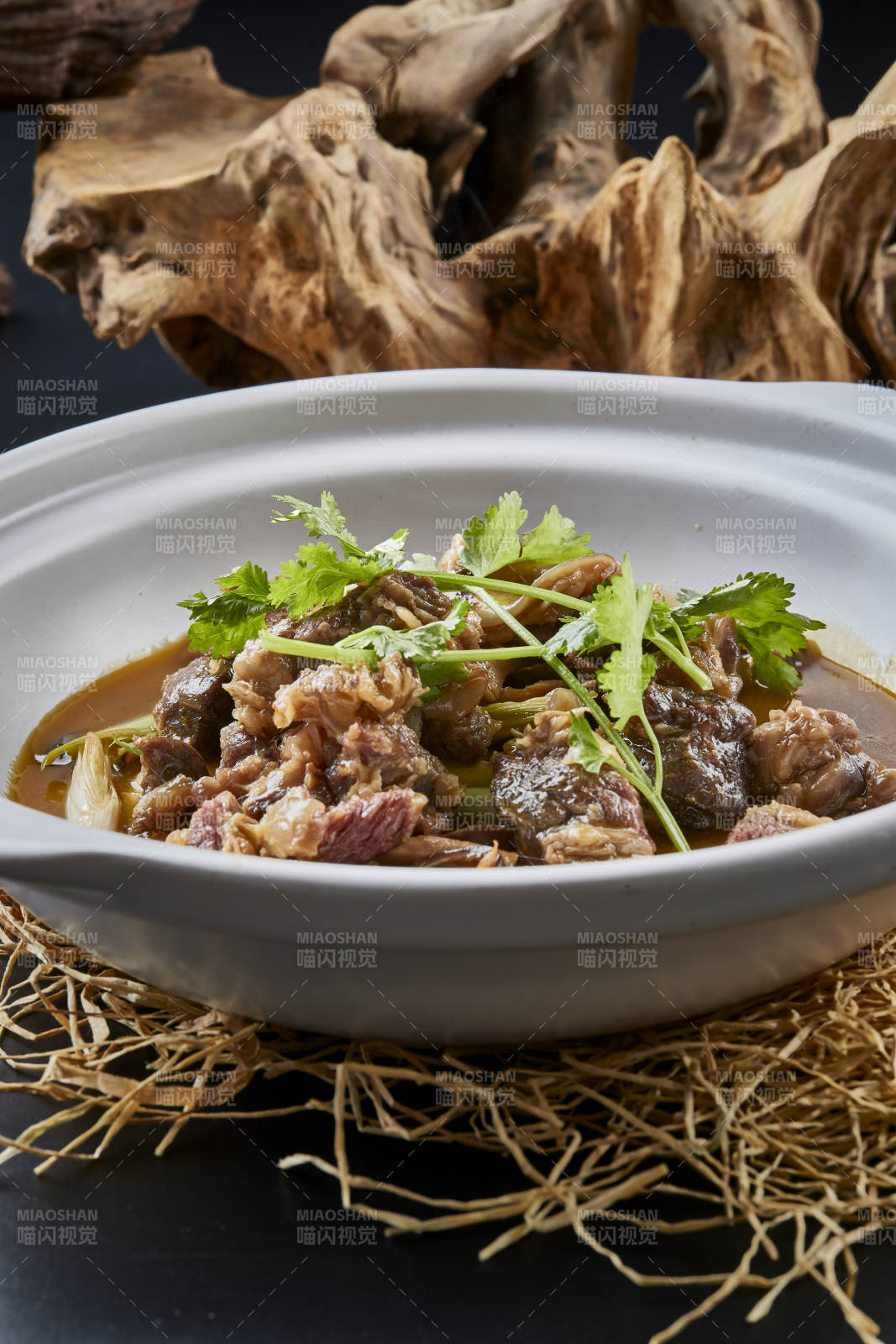 白色砂锅装的蒜苗浓汤炖牛腩