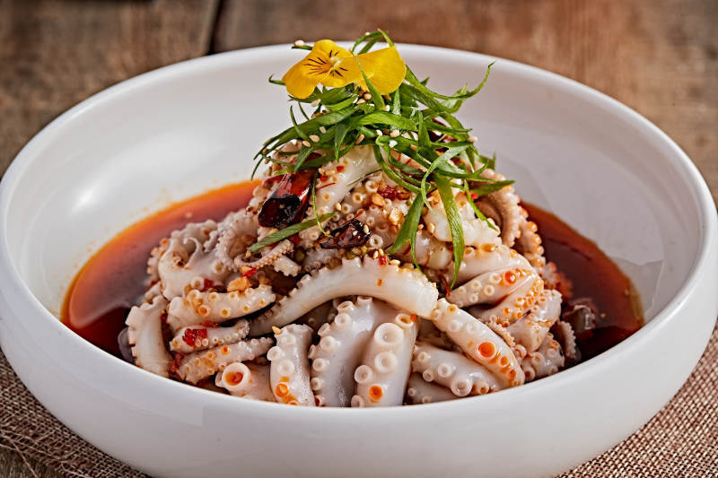 白色瓷盘装的红油醋腌章鱼爪