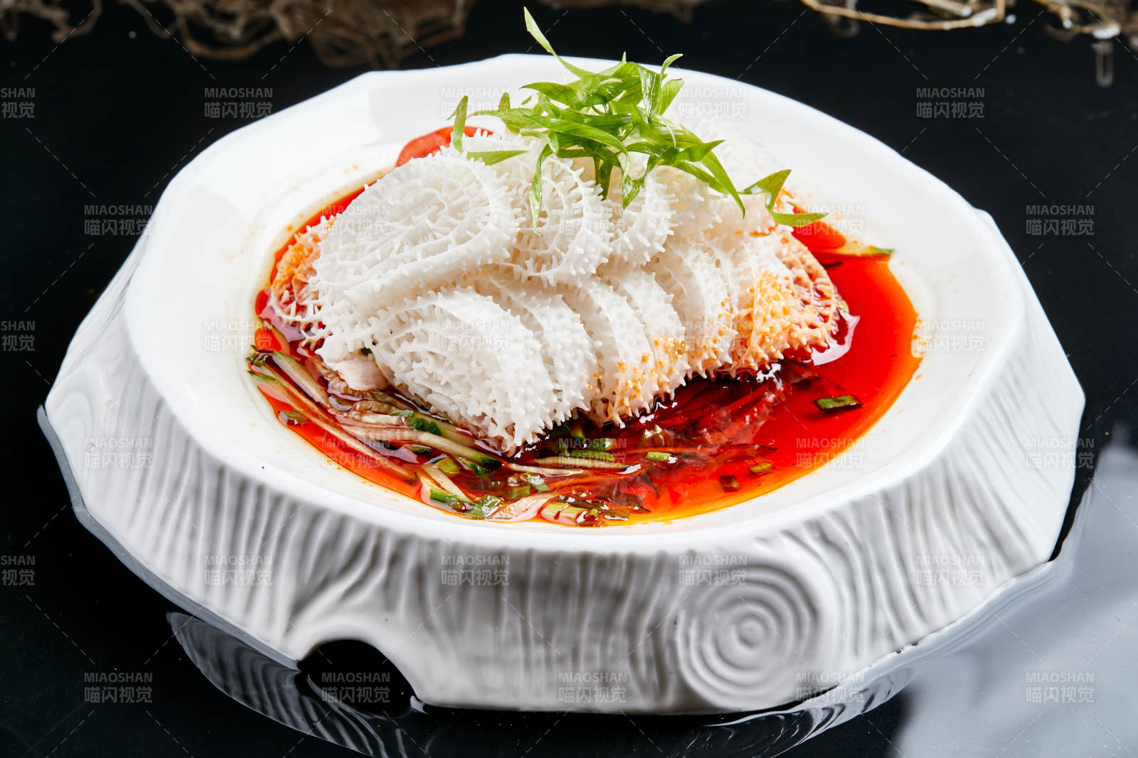 白色瓷盘装的川味红油魔芋肚-摄影图