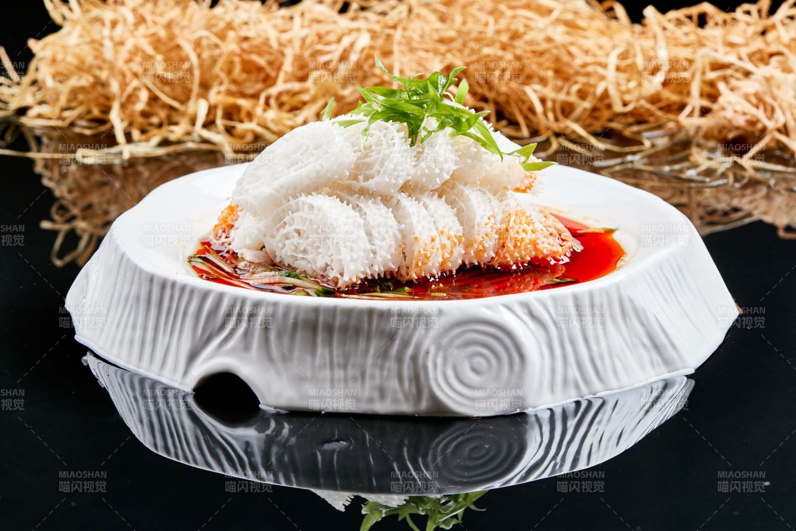 白色瓷盘装的川味红油魔芋肚-摄影图