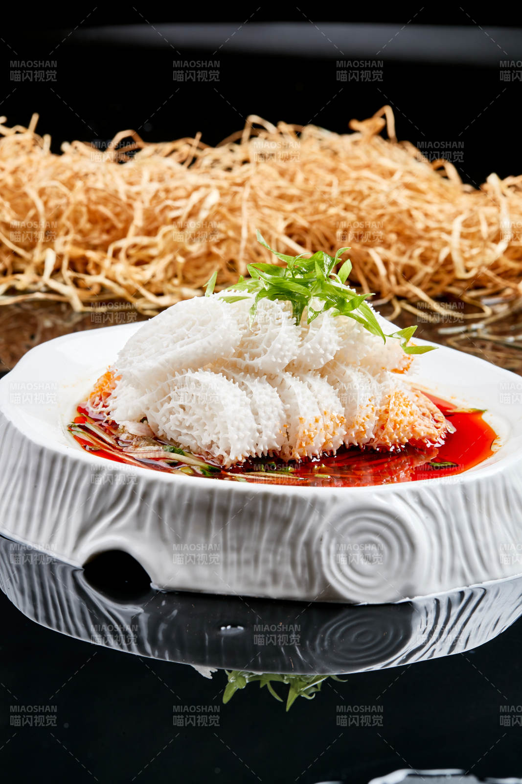 白色瓷盘装的川味红油魔芋肚-摄影图