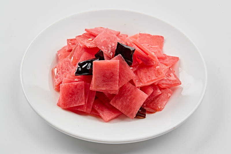 白色瓷盘装的红醋香辣萝卜皮