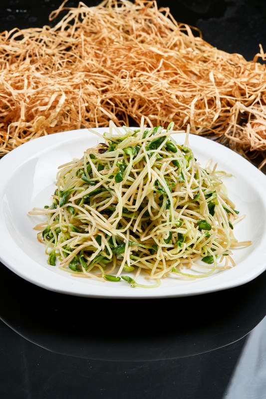 白色瓷盘装的凉拌香椿黑豆苗