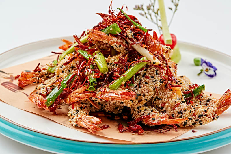 白色瓷盘装的油炸椒盐芝麻深海虾