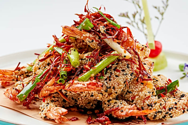 白色瓷盘装的油炸椒盐芝麻深海虾