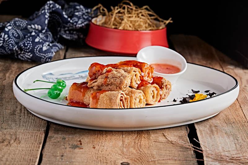 白色瓷盘装的浇汁油炸干豆腐卷