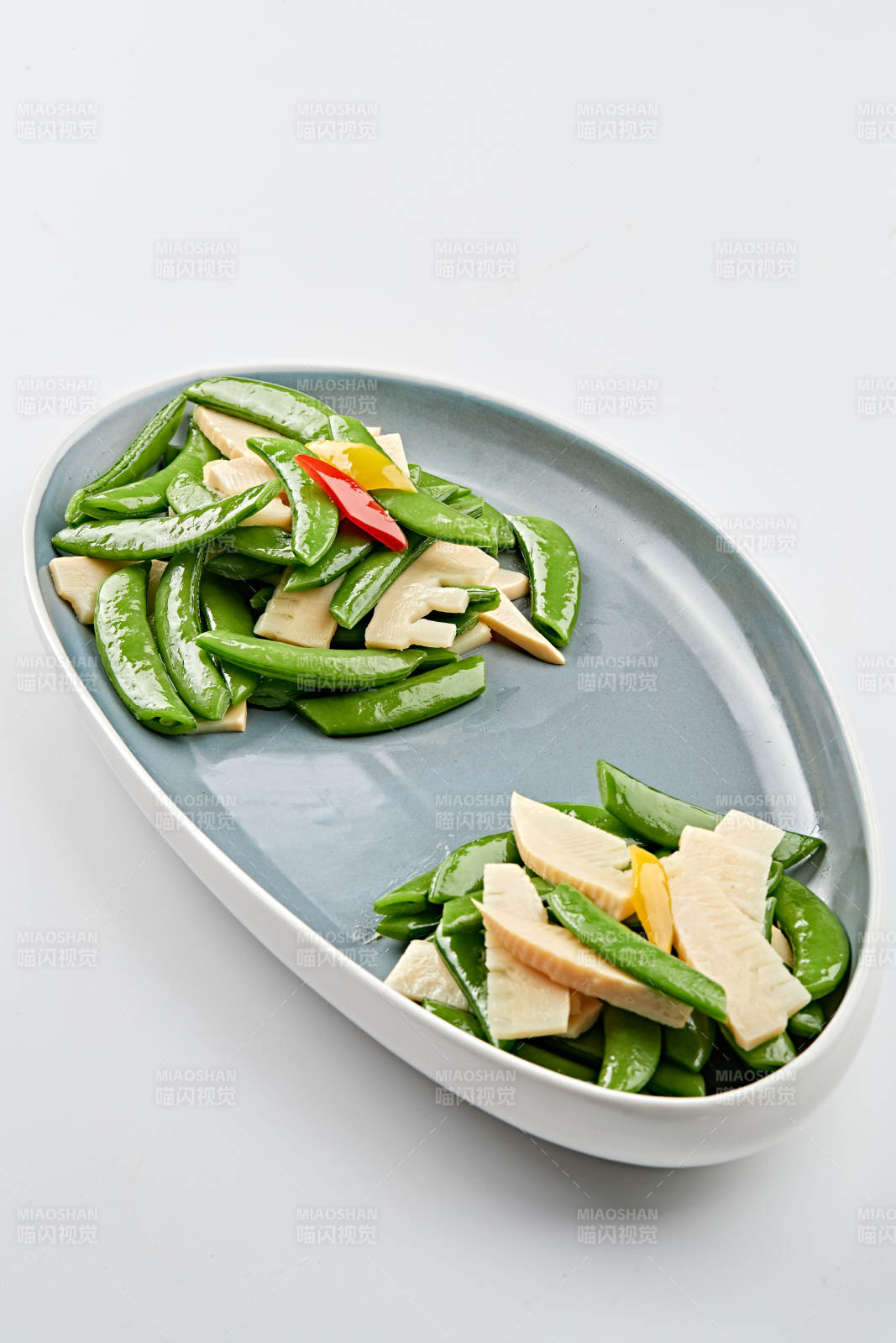 精美瓷盘装的冬笋彩椒炒蜜豆
