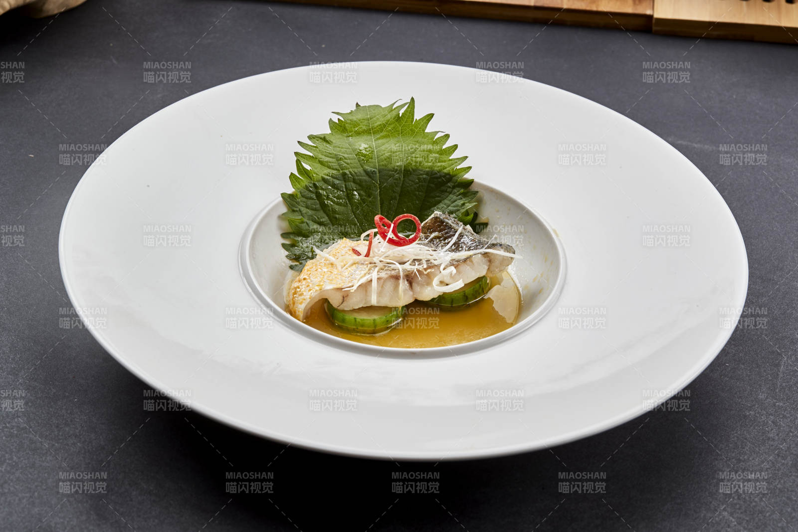 白色圆瓷盘装的位菜紫苏叶配鲜汤鱼块图片