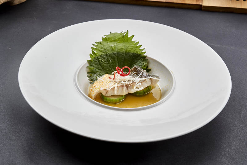 白色圆瓷盘装的位菜紫苏叶配鲜汤鱼块