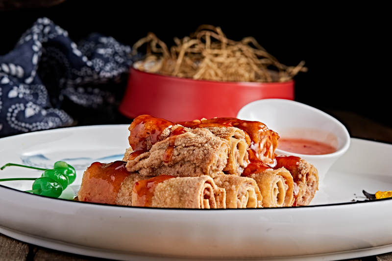 白色瓷盘装的浇汁油炸干豆腐卷