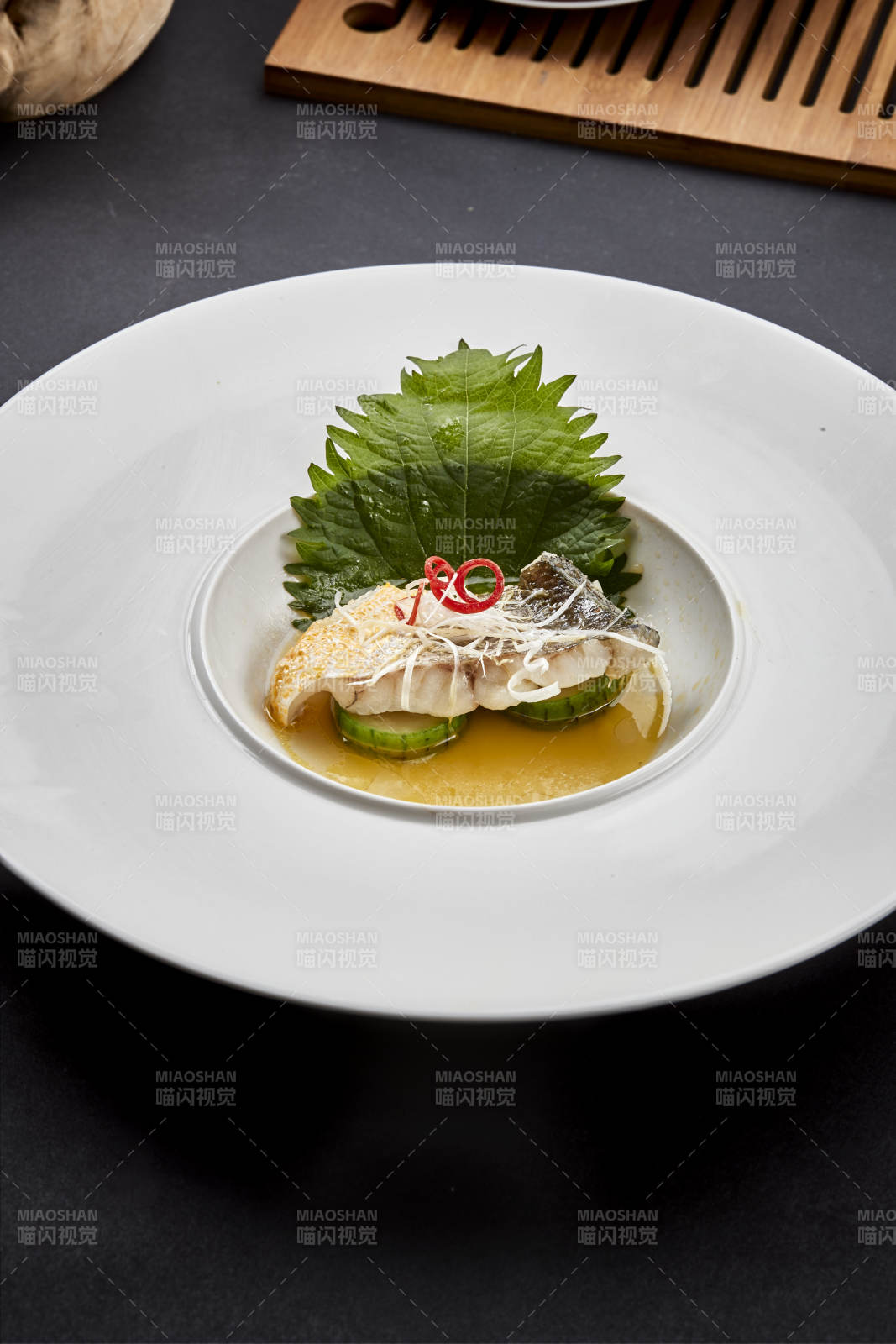 白色圆瓷盘装的位菜紫苏叶配鲜汤鱼块