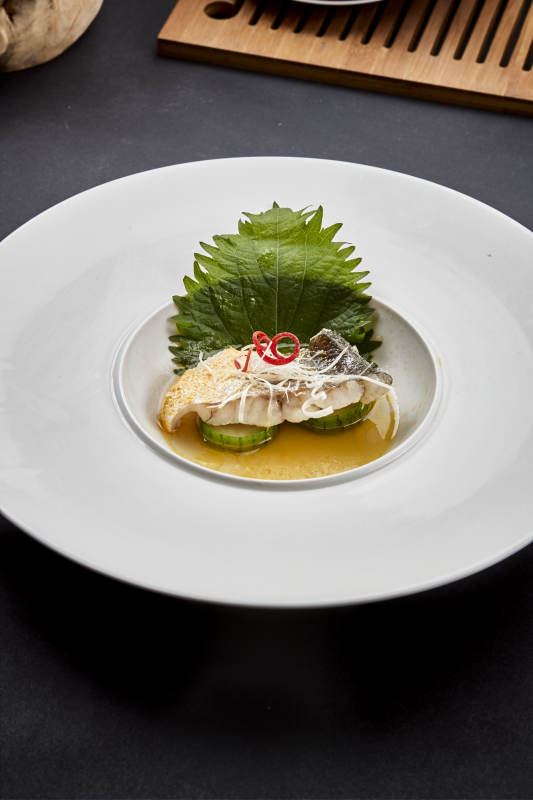 白色圆瓷盘装的位菜紫苏叶配鲜汤鱼块