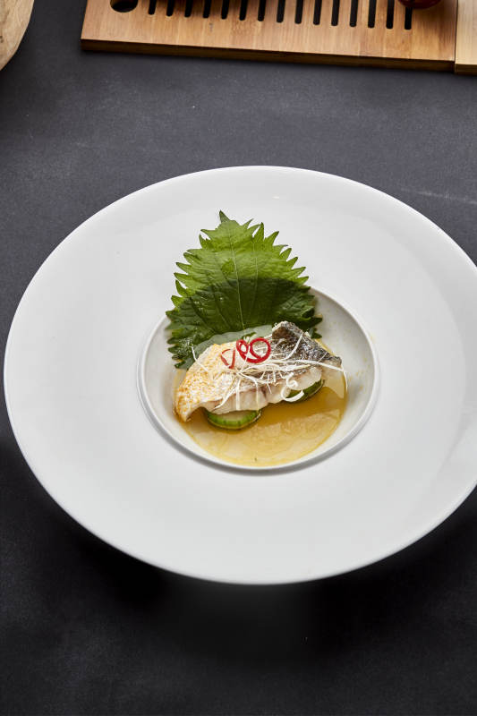 白色圆瓷盘装的位菜紫苏叶配鲜汤鱼块