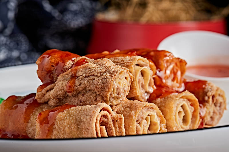 白色瓷盘装的浇汁油炸干豆腐卷