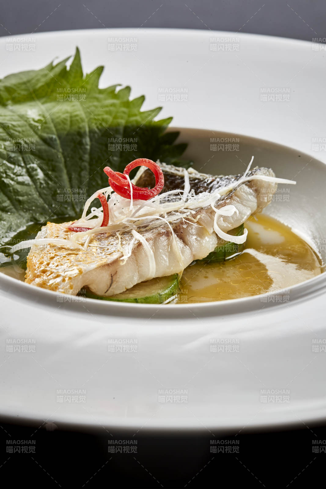 白色圆瓷盘装的位菜紫苏叶配鲜汤鱼块