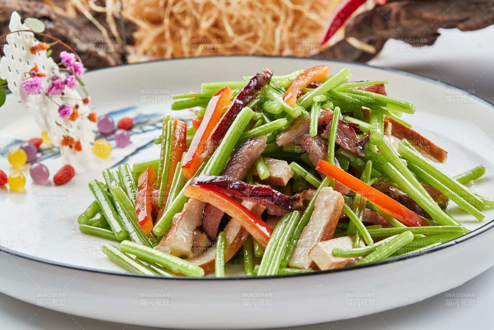 白色瓷盘装的腊肉彩椒茼蒿炒熏干子