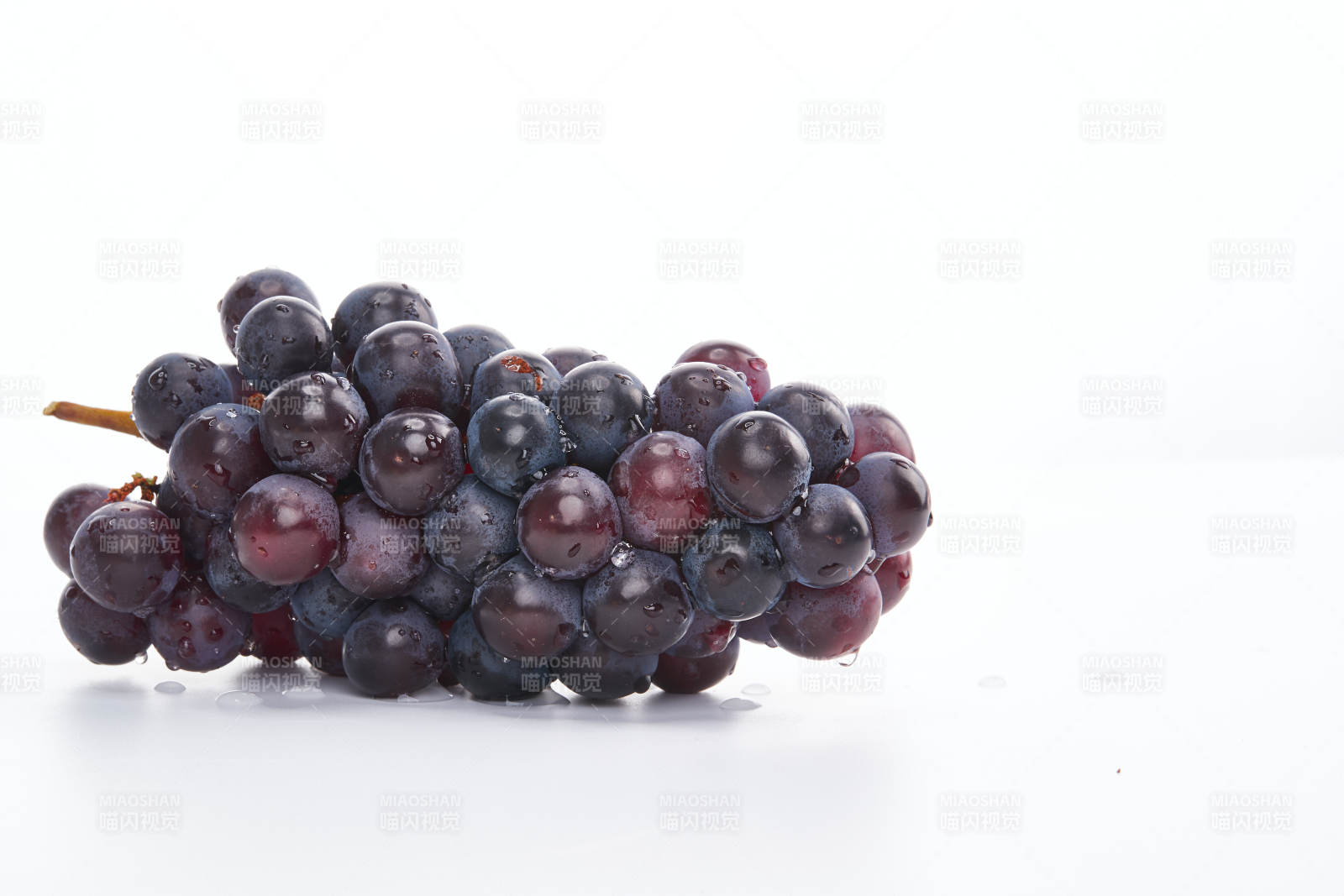 白色背景上摆放的水嫩新鲜紫葡萄