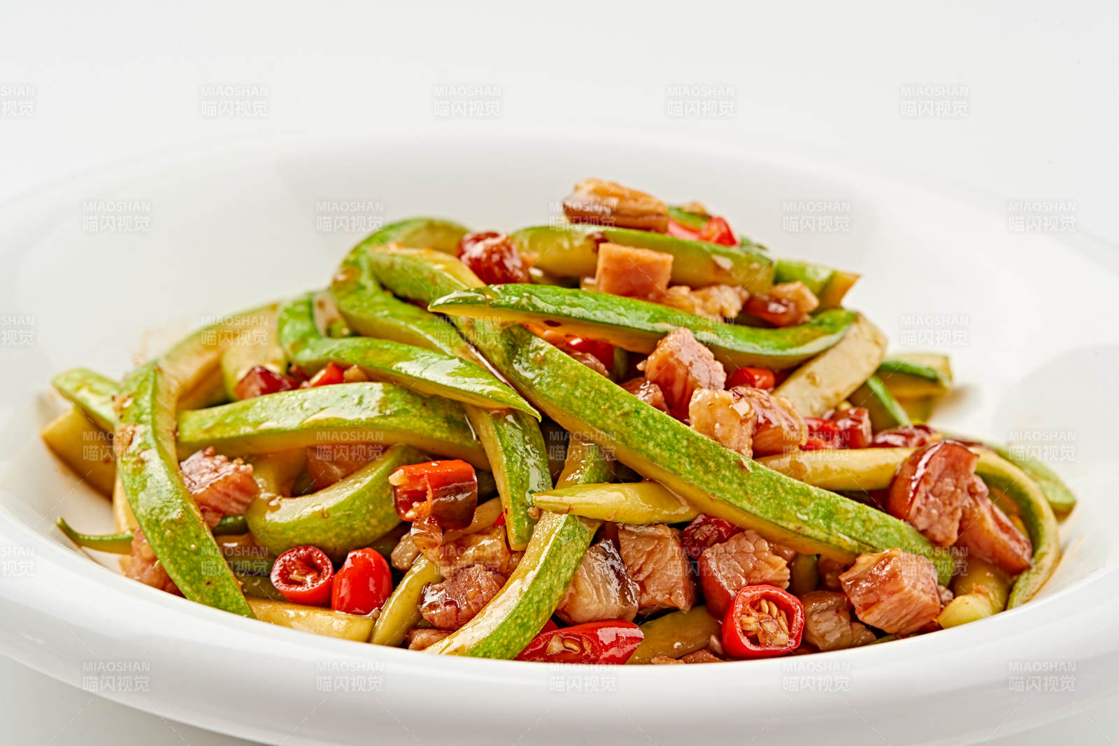 白色瓷盘装的葫芦条米椒炝炒腊肉丁图片