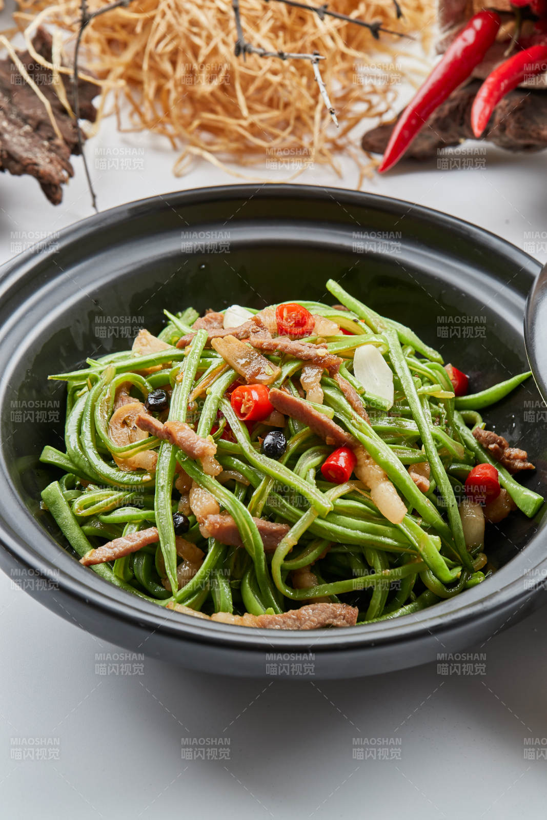 黑色砂锅装的米椒肉丝煲豇豆丝