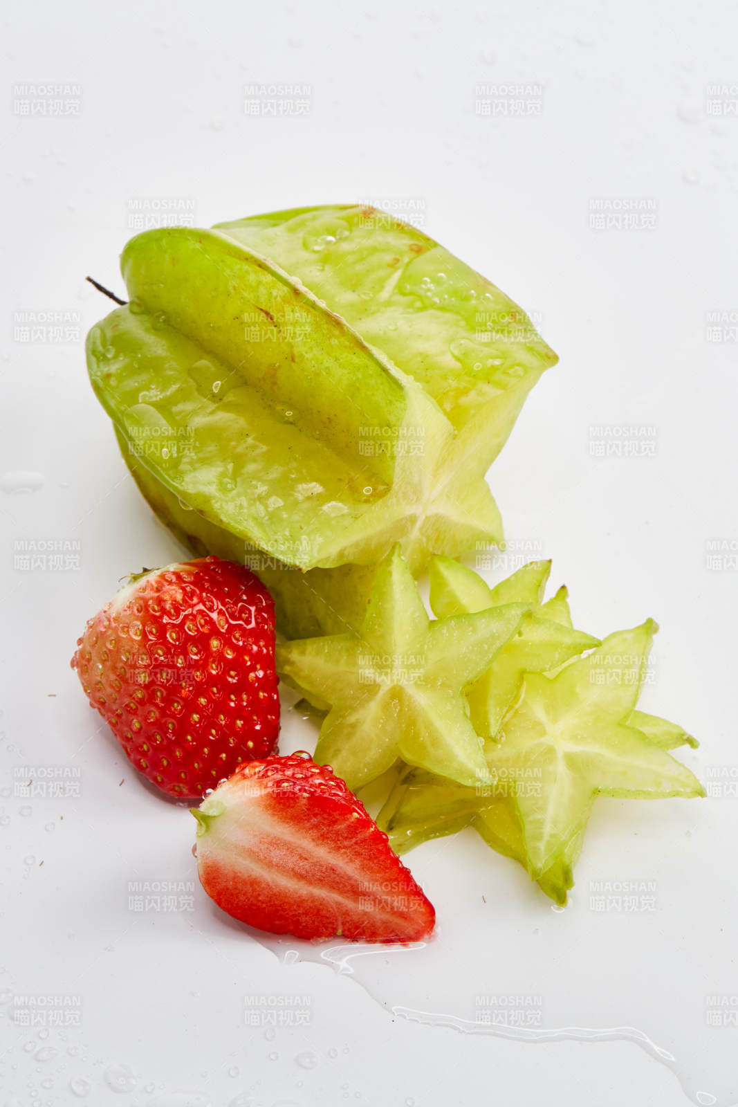白色背景上摆放的新鲜洋桃和草莓及切片
