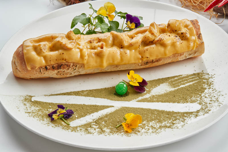 白色瓷盘装的的芝士火腿焗法棍面包