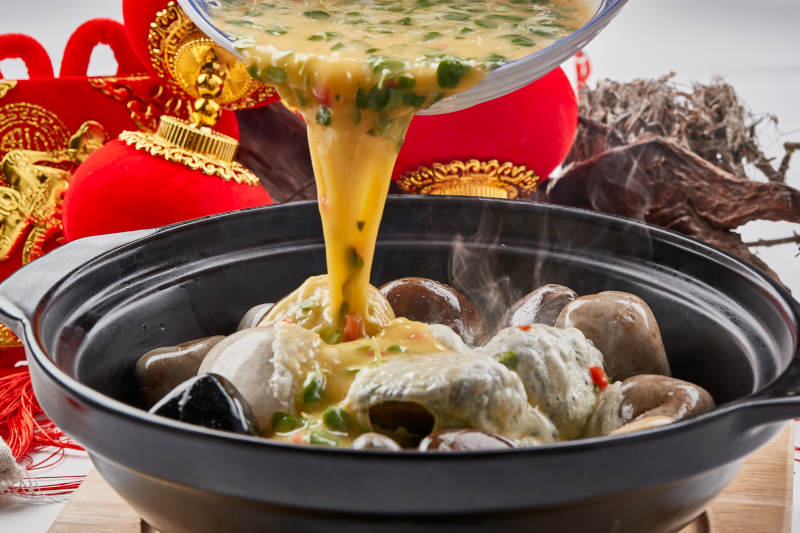 黑色砂锅装的创意美食鸡蛋碰石头