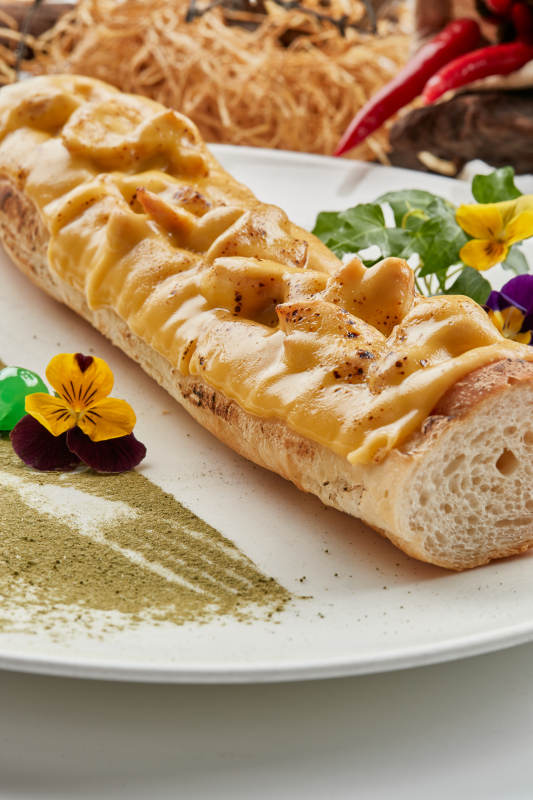 白色瓷盘装的的芝士火腿焗法棍面包