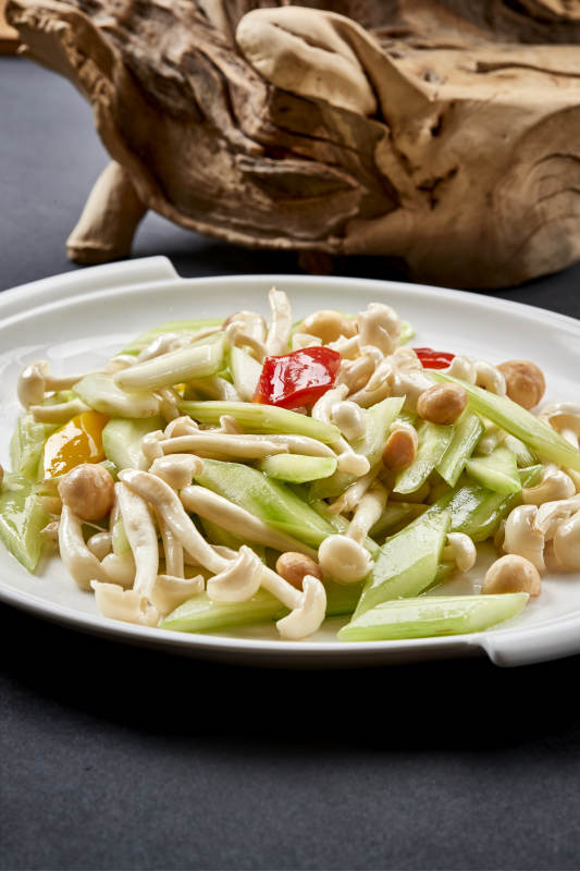 圆瓷盘装的西芹彩椒小炒白玉菇